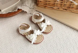 Gros plan de sandales de princesse blanches pour filles avec nœuds et dentelle