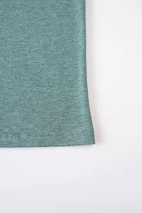 Gros plan sur la texture du tissu et l'ourlet d'un t-shirt vert en lin et coton pour homme