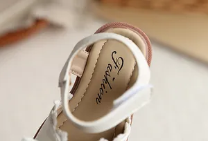 Gros plan de sandales beiges pour filles avec imprimé 'Fashion' et bride Velcro.