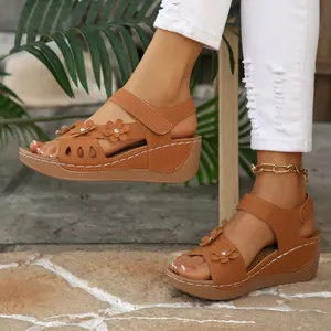 Gros plan de sandales compensées marron pour femmes avec fleurs et semelles plateformes