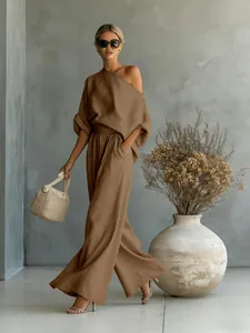 Elegant brown off-shoulder top and wide-leg trousers set styled with a straw bag.