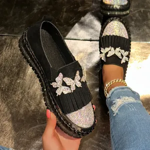Detailansicht eleganter schwarzer Plateau-Loafer mit Strass-Schmetterling und Fransen.