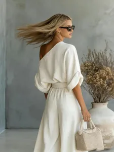 Back view of a stylish off-white one-shoulder top and wide-leg trousers set on a model
