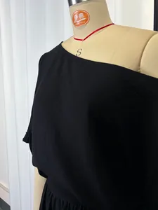 Detailed view of a black off-shoulder loose top displayed on a professional mannequin form
