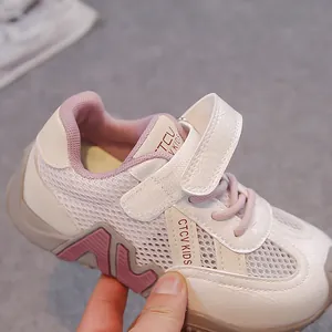 Gros plan d'une basket en maille respirante pour garçon aux tons crème et rose.