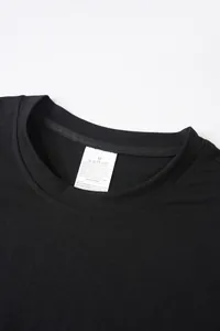 Gros plan du col d'un t-shirt noir avec étiquette d'entretien détaillant la composition