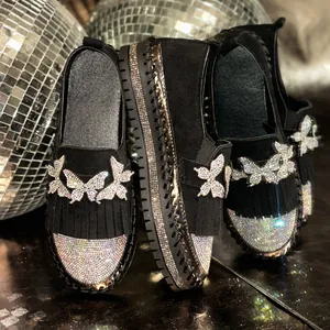 Nahaufnahme von glitzernden Strass-Schmetterlingen auf schwarzen Loafers mit Fransen