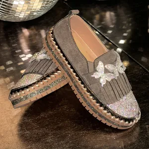 Detailaufnahme grauer Plateau-Loafer mit Strass-Schmetterlingen und Fransen-Akzenten.