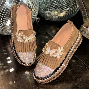 Detailaufnahme von braunen Wildleder-Loafern mit Fransen und glitzernden Schmetterlingen.