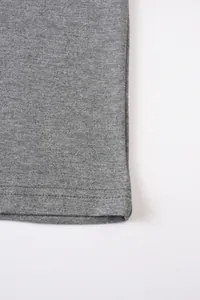 Gros plan sur l'ourlet à double couture et la texture du tissu gris chiné d'un t-shirt homme.