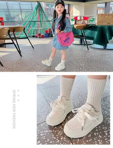 Detaillierte Nahaufnahme von weißen Kinder-Sneakern aus Leder mit Klettverschluss und Schnürsenkeln.