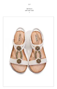 Detailed view of bohemian wedge sandals with white elastic straps and rhinestone floral accents