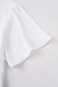 Détail en gros plan de la couture de manche d'un t-shirt blanc en coton pour homme.