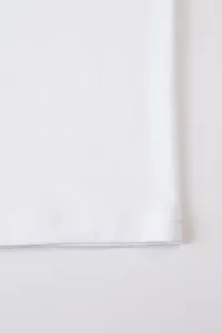 Gros plan sur l'ourlet inférieur d'un t-shirt blanc en coton et lin avec double couture.