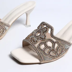 Gros plan de mules à talons blanc cassé élégantes avec motifs floraux brillants en strass