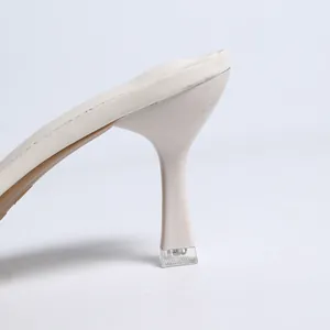 Gros plan sur un talon aiguille blanc cassé élégant avec bout transparent pour femme
