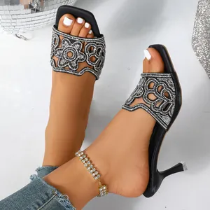 Gros plan sur d'élégantes sandales noires à talons hauts avec motifs de fleurs en strass