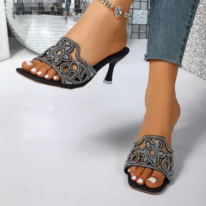 Vue détaillée d'élégantes mules noires avec des motifs floraux en strass scintillants.