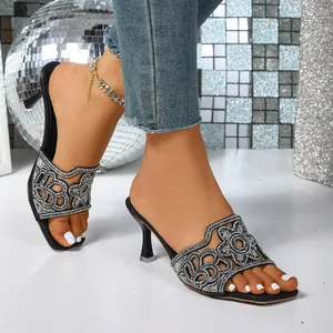 Détail rapproché du motif floral en strass étincelants sur les sandales noires à talons