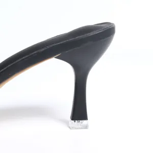 Vue rapprochée d'une sandale noire à talons hauts avec un embout de talon en cristal clair