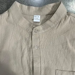 Primo piano di camicia Henley in lino beige con colletto, bottoni ed etichetta taglia M