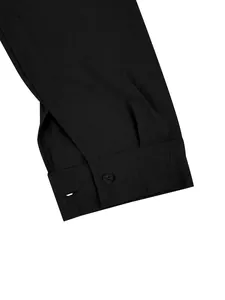 Dettaglio del polsino di una camicia nera in lino con bottone e tessuto tramato