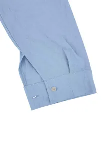 Dettaglio macro che mostra la trama e il bottone del polsino di una camicia di lino