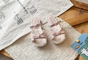 Detail view of pink girls' sandals featuring elegant bows and delicate floral pattern insoles