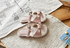 Top view detail of pink girls' sandals featuring elegant double bowknots and floral insoles.