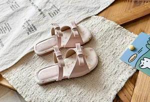Detailed view of stylish pink girls' sandals featuring elegant bows and floral insoles