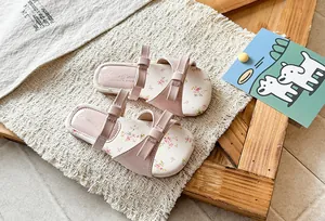 Detailed view of pink girls' sandals featuring cute bow accents and floral print insoles.