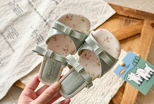 Macro view of sage green girls' sandals featuring triple bows and floral print details