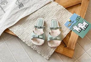 Detail view of green girls' sandals featuring bows and delicate floral print insoles.