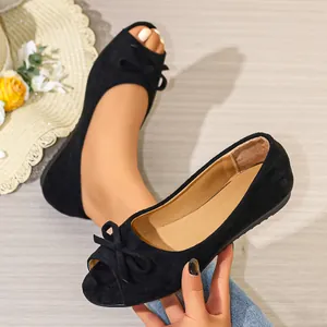 Close-up of elegant black suede peep-toe flat shoes with a decorative bow detail
