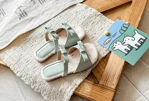 Macro view of mint green girls' summer sandals with cute bows and floral insole patterns.