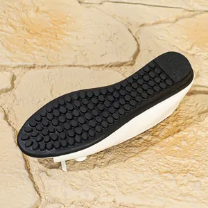 Detailed macro shot of white leather flat shoe with non-slip black pebbled rubber sole