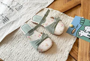 Close-up of sage green kids' sandals with floral insole and decorative bow