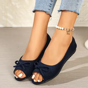Close-up view of elegant navy blue suede peep-toe flats with a stylish bow on a model