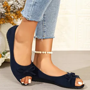 Close-up detail of navy blue suede flat sandals with elegant bow and peep toe design