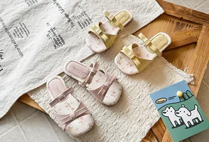 Detailed view of girls' bow sandals in pink and yellow with elegant floral patterns