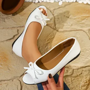 Detailed macro view of white peep-toe ballet flats with decorative bow and soft sole
