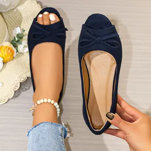 Detailed view of stylish navy blue suede peep-toe flat shoes with a classic bow.