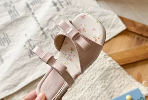 Detailed view of pink girls sandals with elegant bow accents and floral print insole
