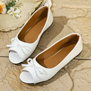 Close-up view of elegant white peep-toe flat shoes featuring a delicate bow detail.