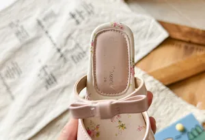 Close-up of girl's sandal featuring pink bowknot and delicate floral pattern on insole