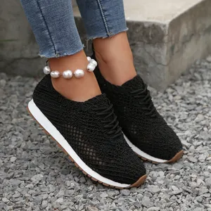 Detailed view of black breathable floral lace-up sneakers for women on gravel ground
