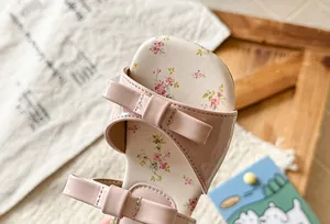 Detail of pink girl's sandal featuring a bow strap and floral print insole