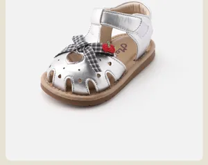 Side view of silver baby girl sandal featuring heart cutouts and a plaid bow detail