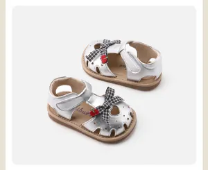 Detail of silver baby girl walking shoes with checkered bows and cute strawberry accents