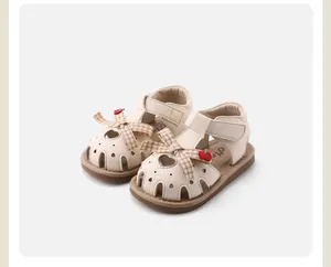Close-up view of soft-sole baby girl closed-toe sandals featuring bowknot and cherry charms